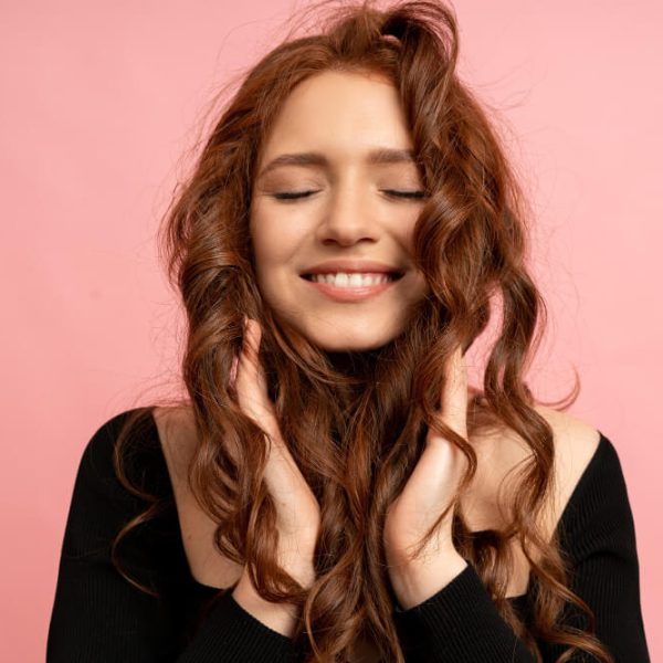 beautiful-red-head-woman-with-close-eyes-posing-pink-wall-wavy-hairs-perfect-smile (1)